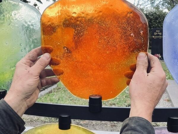 Hände setzen eine Glasscheibe in die Urnengrabanlage HIMMELREICH MEMORIAL ein – STOI Steinmetzwerkstatt