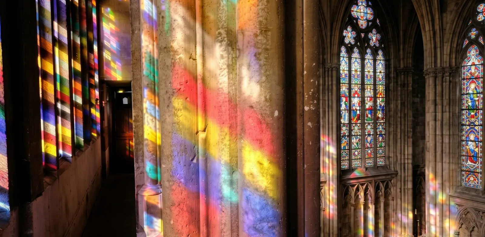 Farbiges Licht der Kirchenfenster fällt auf eine Kirchenwand – STOI Steinmetzwerkstatt