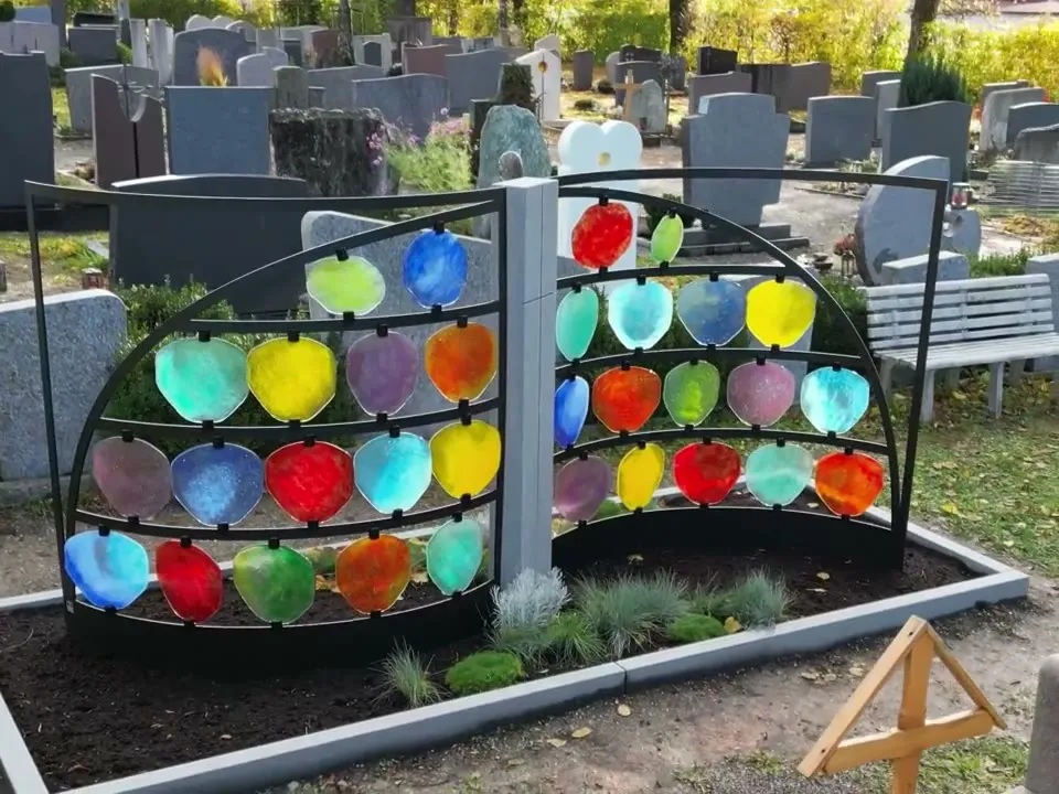 Urnengrabanlage mit bunten Glasscheiben in zwei Bögen von vorne in der Sonne – STOI Steinmetzwerkstatt