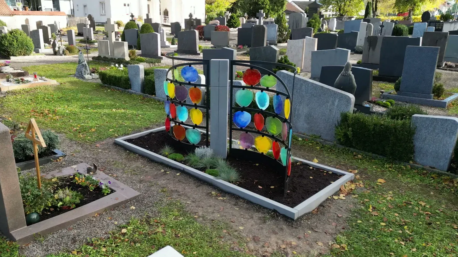 Urnengrabfeld HIMMELREICH MEMORIAL mit bunten Glasscheiben zwischen den Grabreihen des Friedhofs Lenzfried im Herbst – STOI Steinmetzwerkstatt